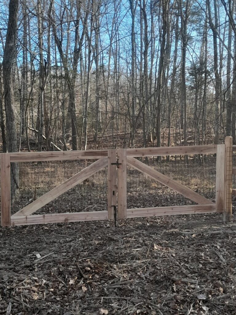 A rustic wood gate with wire mesh, suitable for a rural or wooded property, installed by Aguilarfence services LLC in Clayton, NC.