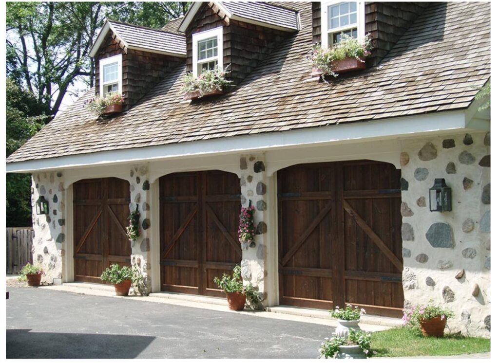 Three rustic wooden carriage-house style garage doors on a stone facade garage, installed by Geiszler Garage Door in Milwaukee, WI.