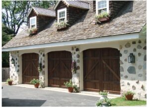 Three rustic wooden carriage-house style garage doors on a stone facade garage, installed by Geiszler Garage Door in Milwaukee, WI.