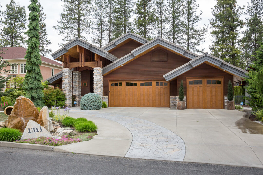 Rustic wooden garage doors with windows and cross-brace design on a home, installed by Continental Door Company, Spokane Valley, WA.