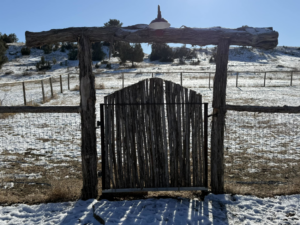 A rustic wooden gate and wire fence in a snowy landscape, installed by Shield Fencing, LLC in Greeley, CO.