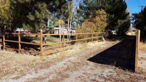 A rustic wooden rail fence installed along a gravel path by Idaho Falls Fencing in Idaho Falls, ID.