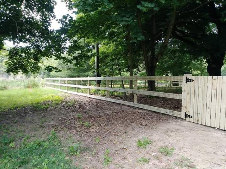 A rustic wooden split rail fence with wire mesh and a wooden gate, installed by A Freedom Fence in Martinsburg, WV.