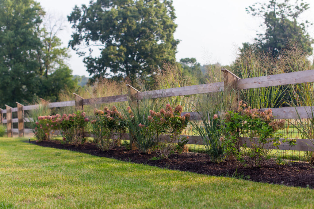 A rustic wooden split rail fence with wire mesh and landscaping installed by Integrous in Gap, PA