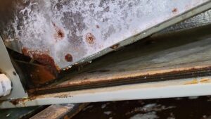 A close-up of a rusty and corroded HVAC drain pan with dripping water, indicating a repair needed from Alien Air Conditioning and Heating in Phoenix, AZ.