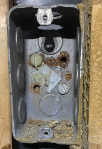 A close-up of a rusty metal electrical junction box, indicating a need for inspection or replacement by Dmac Electric in Detroit, MI