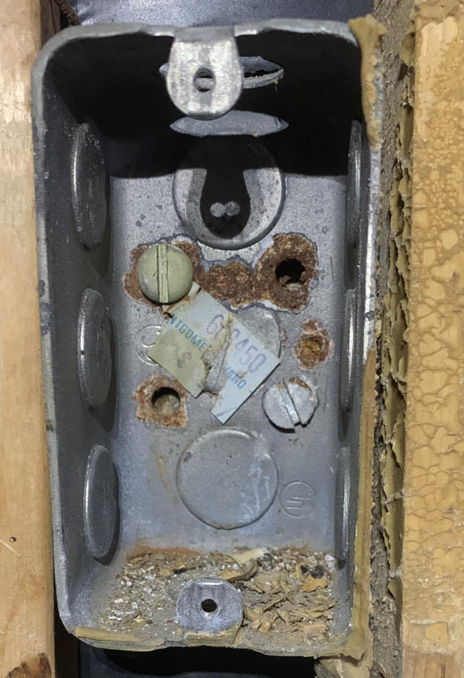 A close-up of a rusty metal electrical junction box, indicating a need for inspection or replacement by Dmac Electric in Detroit, MI