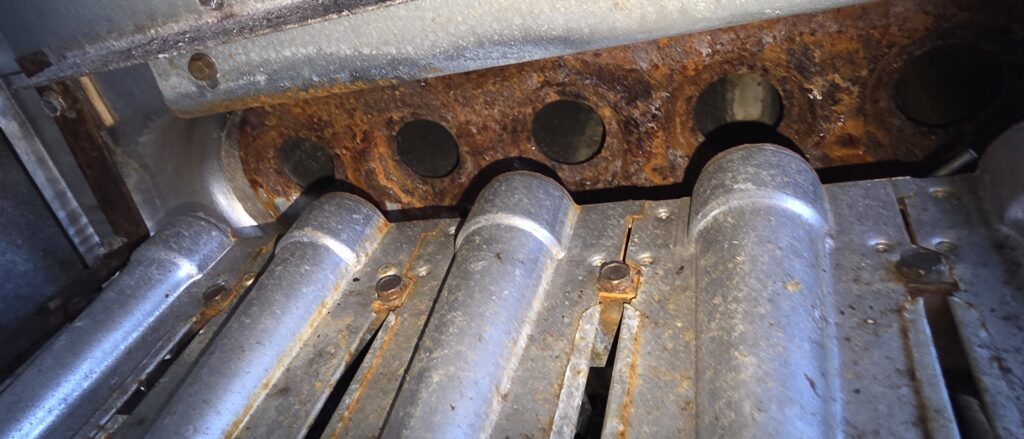 Close-up of a rusty furnace heat exchanger, indicating a repair or inspection by By the Bay Mechanical in Prince Frederick, MD