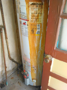 An old, rusty water heater in need of replacement or repair by Cheaper Plumbing & Heating in Lansing, MI