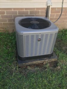 An outdoor Ruud HVAC condenser unit installed next to a brick building by Henson's HVAC LLC in Rock Hill, SC.