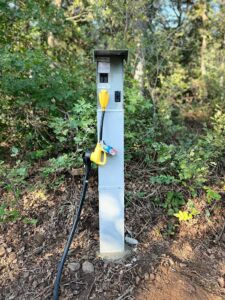 An RV electrical hookup pedestal installed in a wooded area by All Aboard Services in Farr West, UT.