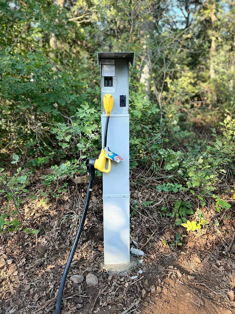 An RV electrical hookup pedestal installed in a wooded area by All Aboard Services in Farr West, UT.