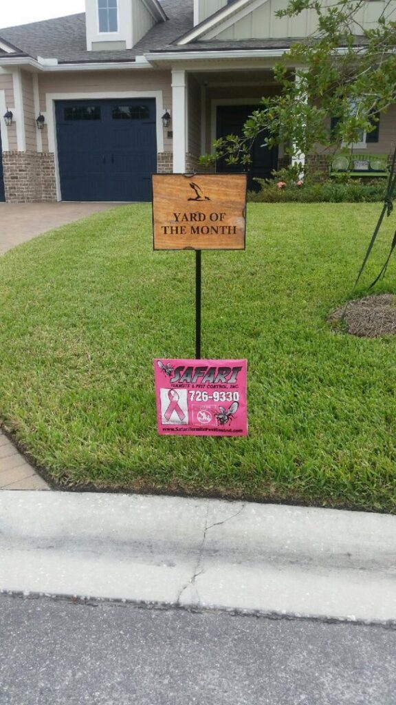 A Safari Termite and Pest Control sign placed beneath a "Yard of the Month" award in Jacksonville, FL.