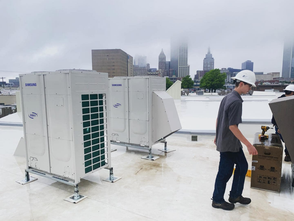 A worker near Samsung HVAC units being installed on a rooftop by Elemental Air in Sanford, FL.