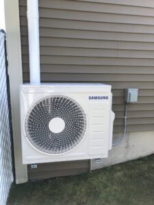 A Samsung mini-split outdoor unit installed on the exterior wall of a home by Garrison City HVACR in Dover, NH