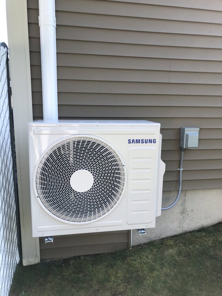 A Samsung mini-split outdoor unit installed on the exterior wall of a home by Garrison City HVACR in Dover, NH