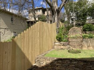 A newly installed scalloped wood picket fence on a sloped residential property by Premier Fence of Birmingham, LLC in Warrior, AL.
