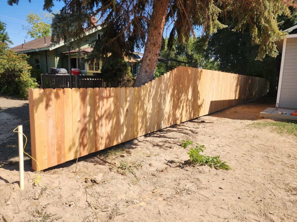 A newly installed scalloped top wooden privacy fence in a backyard by Josey's Fencing LLC in Caldwell, ID.