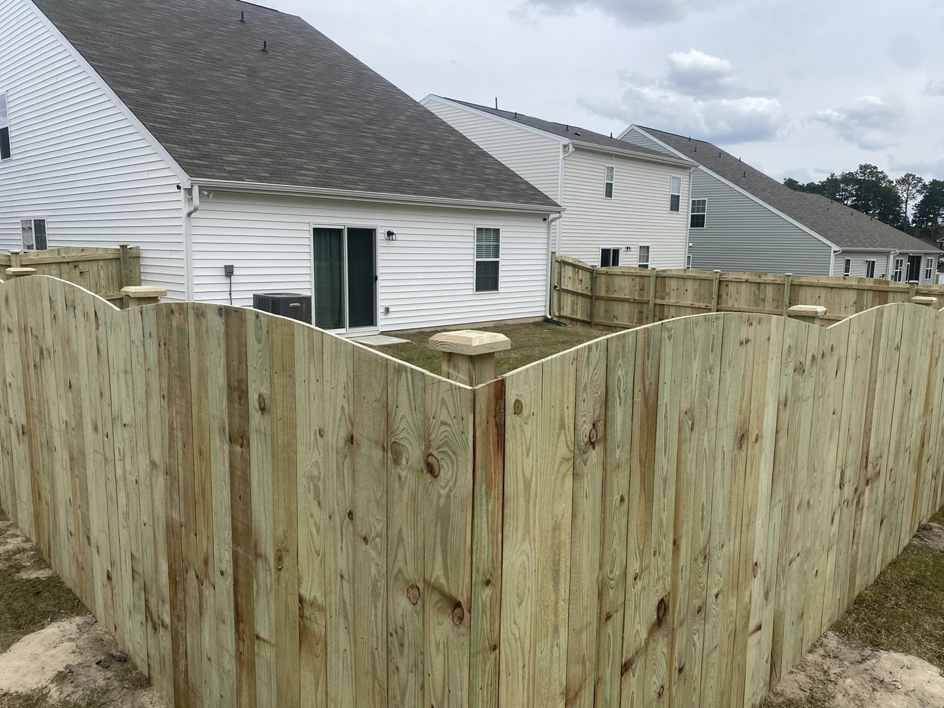 A new scalloped wood privacy fence installed in a residential backyard by Renegade Fencing, LLC in Jacksonville, NC.
