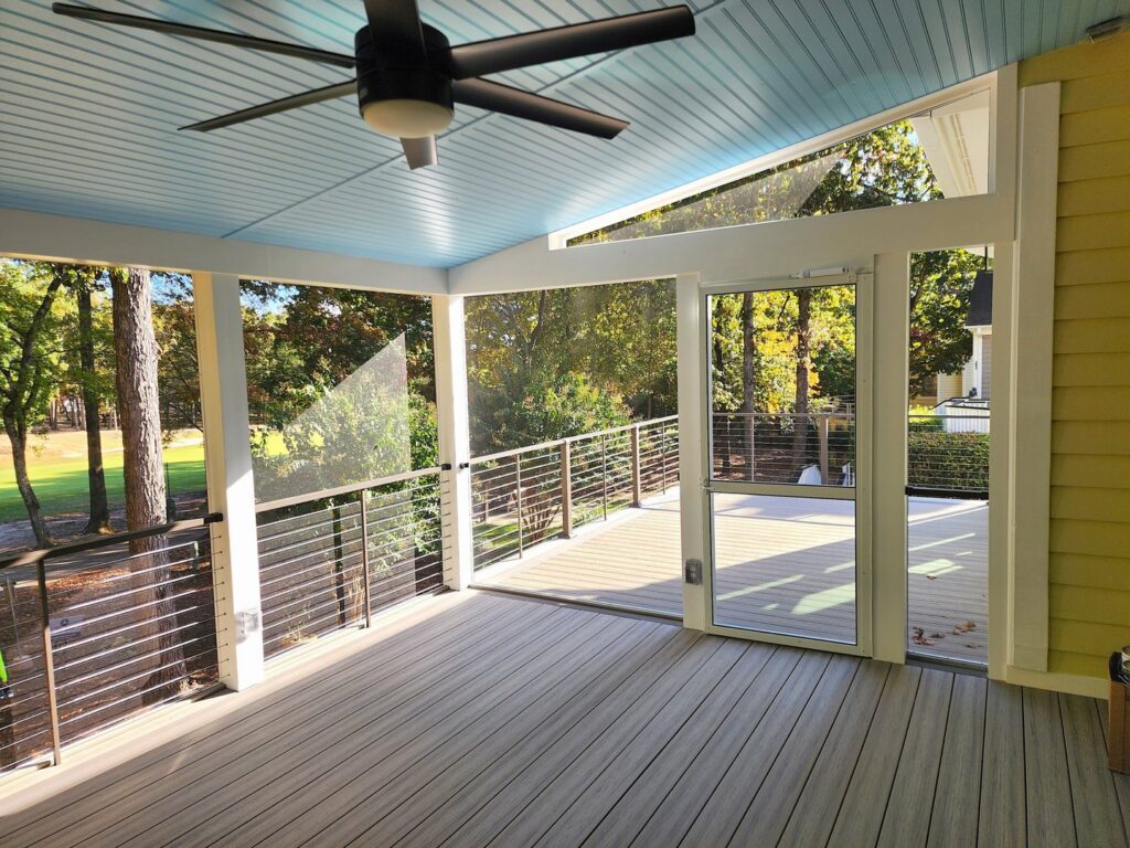 A black ceiling fan installed in a screened porch with a light blue ceiling by True Vine Electric in Raleigh, NC