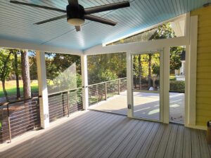 A black ceiling fan installed in a screened porch with a light blue ceiling by True Vine Electric in Raleigh, NC