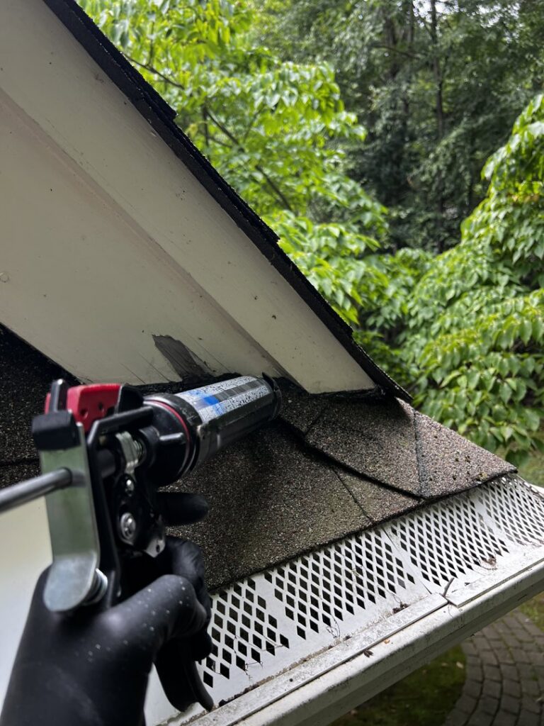 A technician sealing a roofline gap with a caulk gun, performing wildlife exclusion for Defense Pest and Wildlife Control in Hartford, CT.