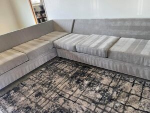 A sectional sofa and area rug showing cleaning patterns after service by Floor Medics in Huntsville, AL