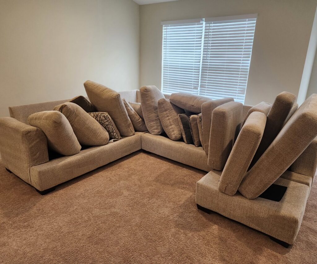 A sectional sofa with cushions stacked, preparing the carpeted area for cleaning by Pure Steam Carpet Cleaning in Nashville, TN