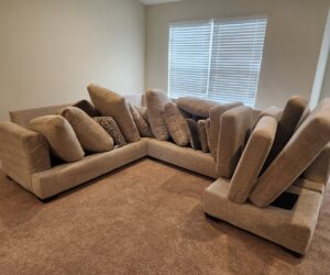 A sectional sofa with cushions stacked, preparing the carpeted area for cleaning by Pure Steam Carpet Cleaning in Nashville, TN