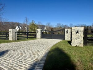 A secure estate entrance featuring closed black metal gates and stone pillars by Heron Building Co in Franklin, TN.