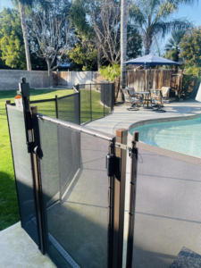 A secure pool enclosure with a self-latching gate, providing safety in a sunny backyard by A Safe Pool Enclosures in Bakersfield, CA.