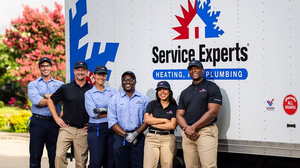 A team of HVAC and plumbing technicians from Komfort Air Service Experts standing in front of their service truck in Charlotte, NC.