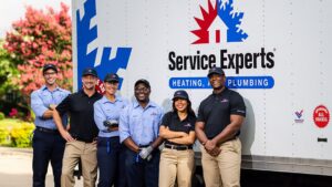 A team of HVAC and plumbing technicians from Komfort Air Service Experts standing in front of their service truck in Charlotte, NC.