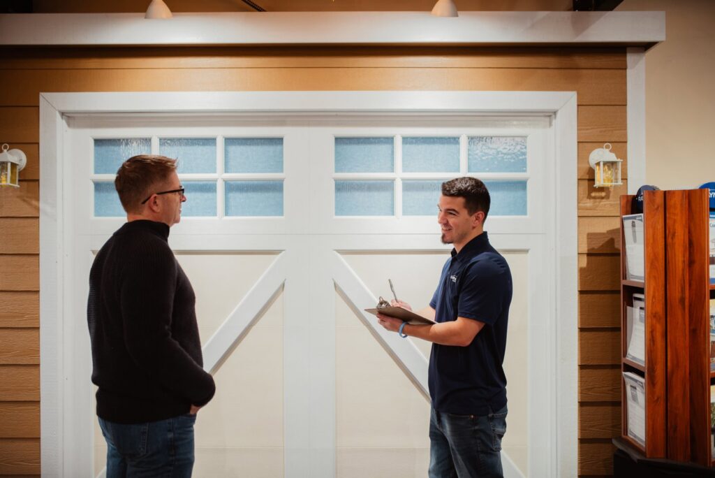 A Front Range Raynor Garage Door & Service representative consulting with a customer in front of a garage door display in Fort Collins, CO.