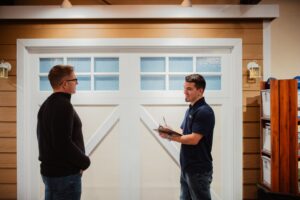 A Front Range Raynor Garage Door & Service representative consulting with a customer in front of a garage door display in Fort Collins, CO.