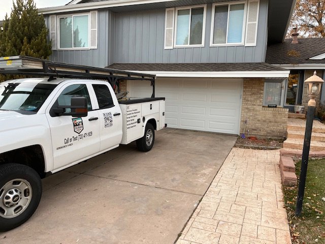 A Colorado Garage Door Guy service truck parked at a residential job site in Aurora, CO.