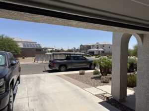 A service truck with a ladder rack parked outside a garage, indicating a job site for MGG Garage Door Service in San Tan Valley, AZ