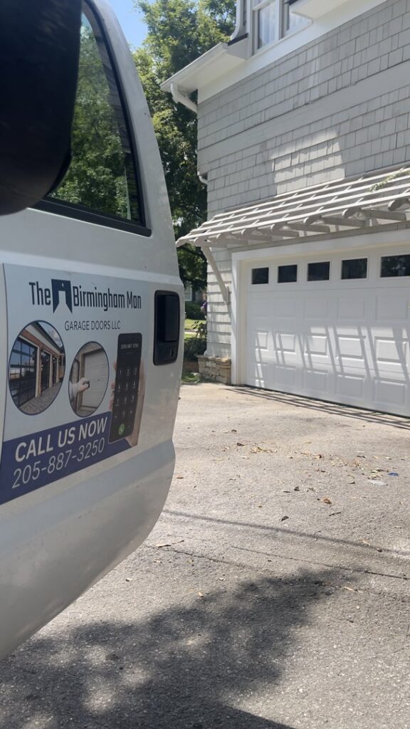 The Birmingham Man Garage Doors service truck parked at a job site with a white garage door in Birmingham, AL.