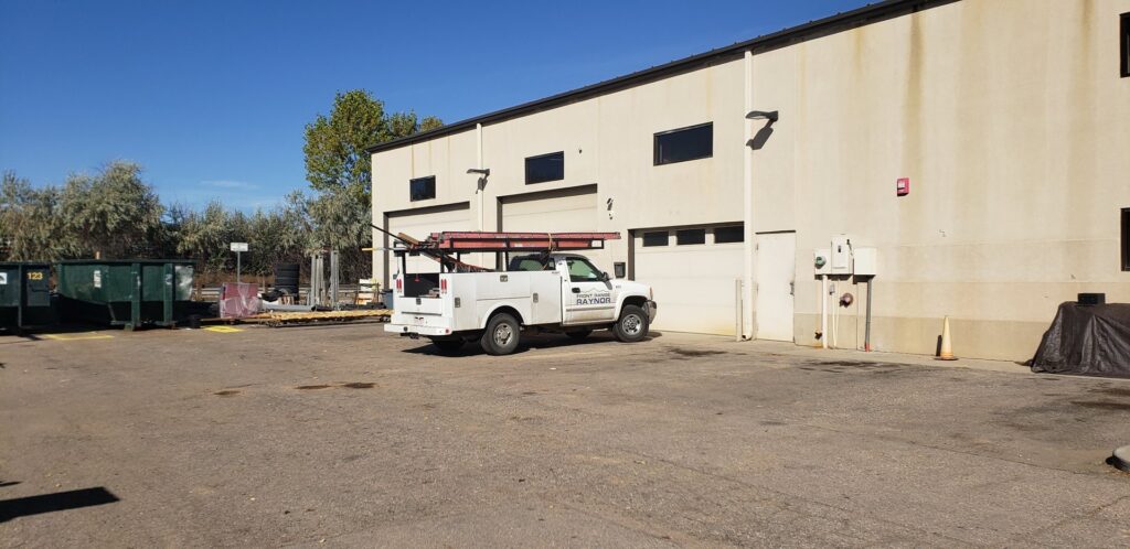 A Front Range Raynor Garage Door & Service truck parked at a commercial building for a garage door job in Fort Collins, CO.