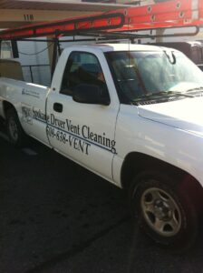 A white service pickup truck with 'Spokane Dryer Vent Cleaning' branding and a ladder on the roof rack, ready for a job in Spokane, WA.