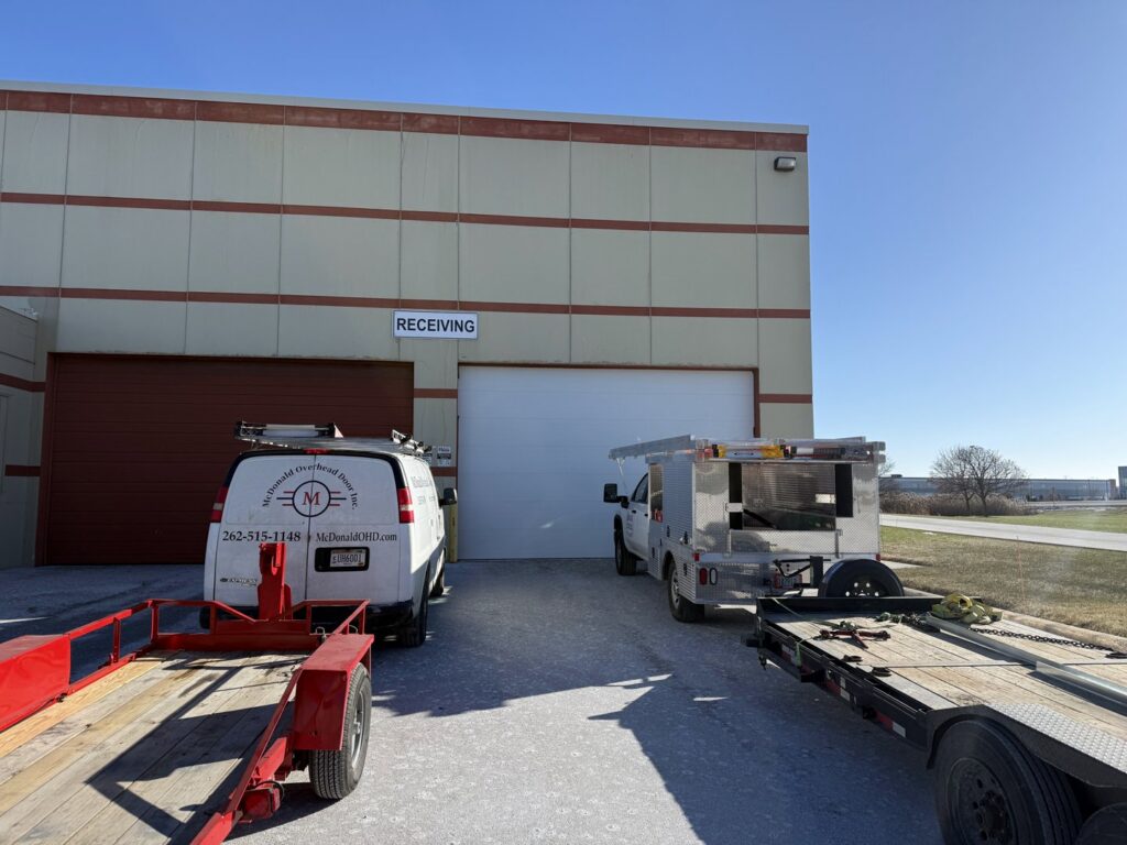McDonald Overhead Door Inc. service trucks parked at a commercial garage door job site in Kenosha, WI.