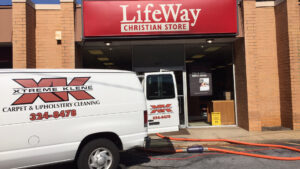 Xtreme Klene Carpet & Upholstery Cleaning service van with hoses running into a commercial building in Montgomery, AL.