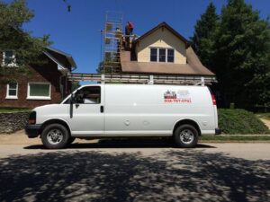 A service van from The Chimney Doctor parked on a street with workers on scaffolding repairing a chimney in Louisville, KY.