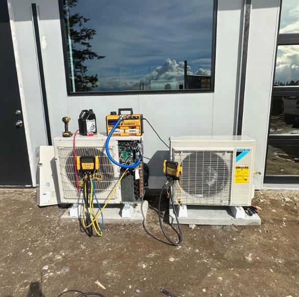 An HVAC technician servicing two outdoor Daikin mini-split units for JN Heating & Cooling in Eure, NC