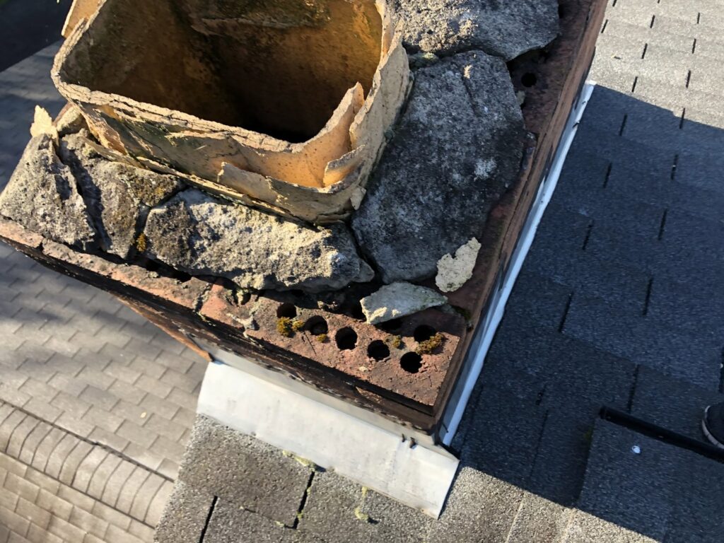 A severely damaged chimney top with a crumbling flue liner and masonry, requiring repair from Al's Chimney Sweep in Pittsburgh, PA.