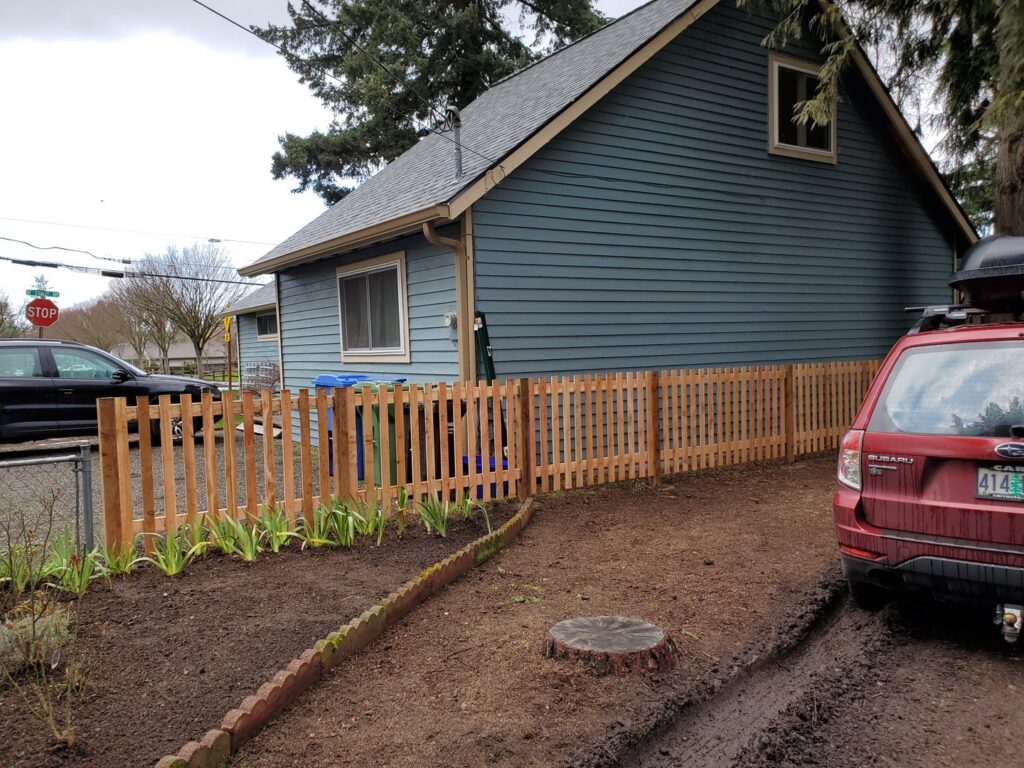 A short wooden picket fence installed along a driveway by Fix-A-Fence LLC in Portland, OR.