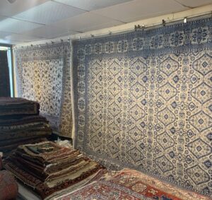 A showroom display featuring numerous hanging and stacked rugs at Danvers Rug in Danvers, MA.