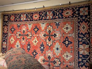 A showroom display featuring large, ornate rugs hanging on a wall at Danvers Rug in Danvers, MA.