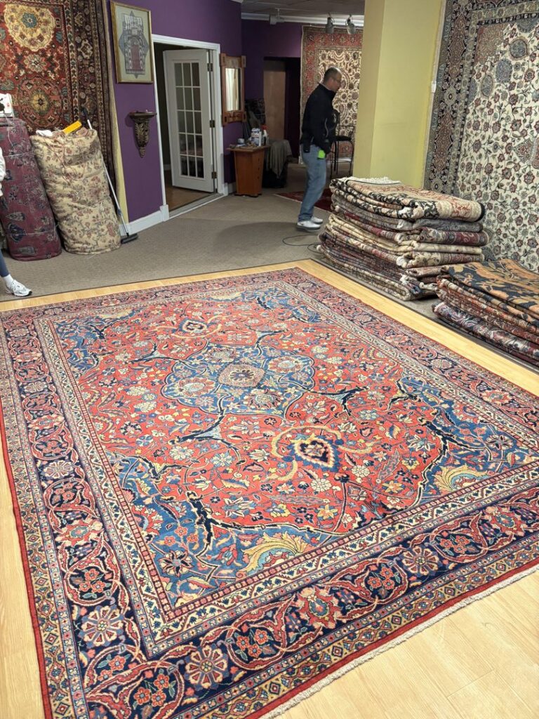 A showroom floor filled with various oriental rugs, some rolled and some laid out, at Accents Galleria in Kansas City, MO