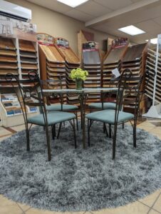 A showroom display featuring a plush round gray rug and various hardwood flooring samples at Petersen's Carpet & Flooring in Frederick, MD